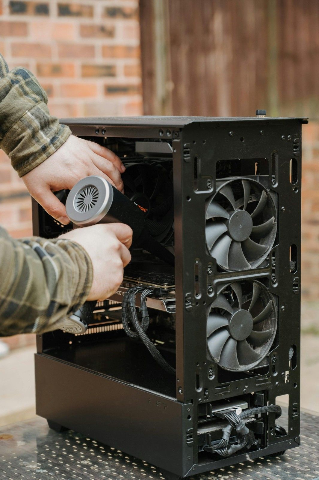 Nettoyage à la main du boîtier d'un ordinateur de bureau avec un plumeau électrique à l'extérieur.